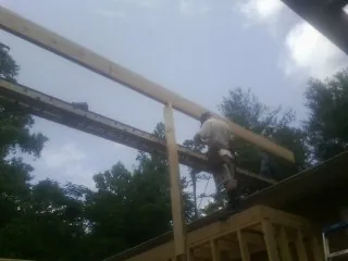 Carpenter setting a ridge beam over a new addition frame — Ice Dam Removal by Roofing Brothers in Morrilton