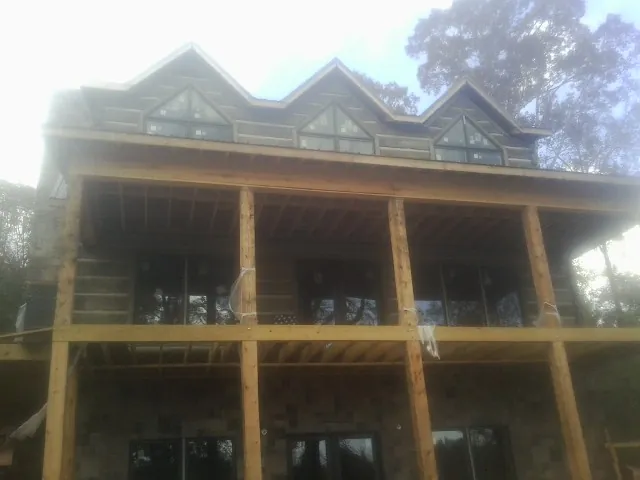 Dormers and porch framing on a large log home under construction — Roof Coating work by our crew in Morrilton