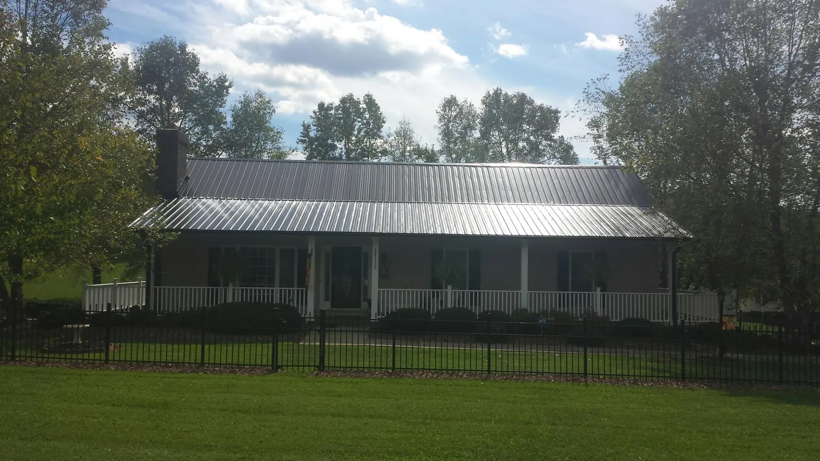 Gray metal roof on a brick ranch with a full width front porch — Gutter Guard Installation work by our crew in Morrilton