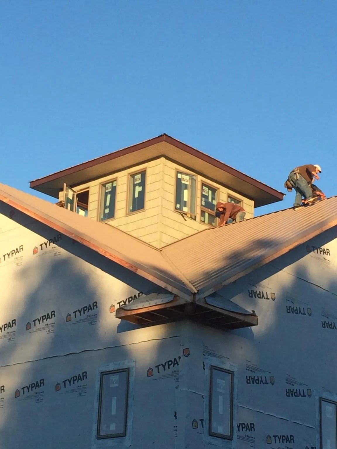 Roofers working around a rooftop cupola on a new metal roof at sunset — Roof Waterproofing in Morrilton by Roofing Brothers